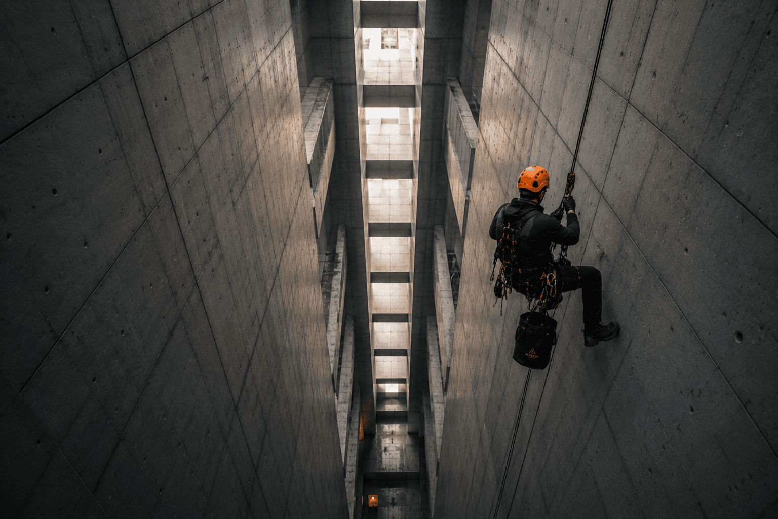 Cordiste en descente à l'intérieur d'un silo industriel en béton brut